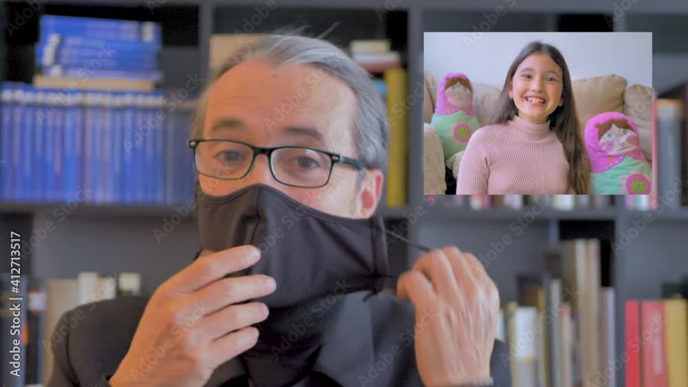 Padre con mascarilla habla por vídeo con su hija confinada