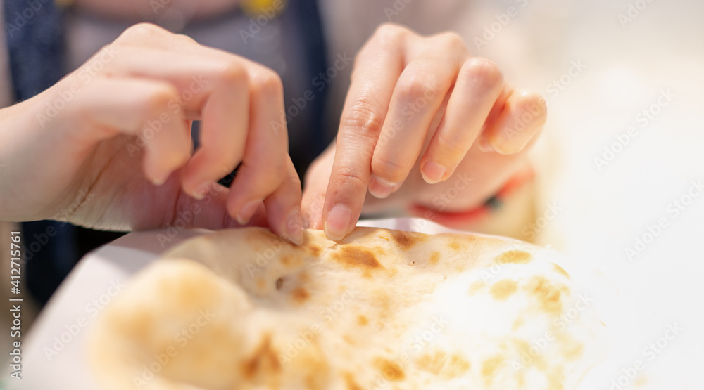 Female hand tearing of a piece of nan bread and preparing to eat with the egyptian food, The culture food concept.