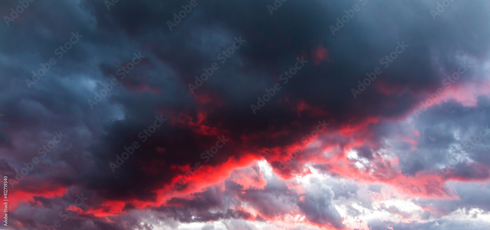 Stunning clouds. Dramatic and spectacular gray and red clouds illuminated by sunset or sunrise, sunrise or sunset colors. Stunning sky landscape background.