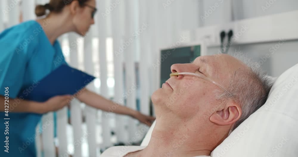 Close up of aged patient with nasal breathing tube sleeping in hospital bed