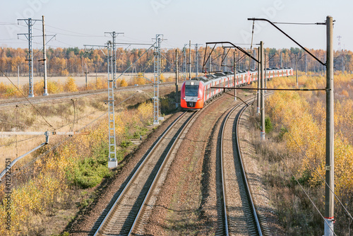 Passenger train approaches to the station at autumn day.