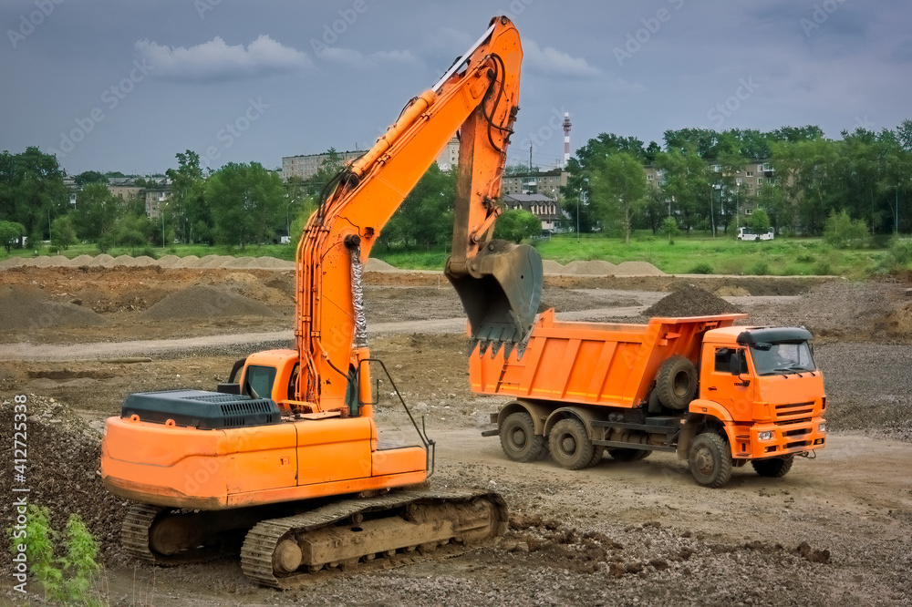 Orange excavator and orange dump truck at a construction site. Orange excavator and orange dump truck at a construction site.