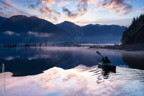 Adventurous Girl kayaking on an infatable kayak in a beautiful lake. Colorful peaceful Sunrise Art Render. Taken in Stave Lake, East of Vancouver, British Columbia, Canada. Adventure, vacation concept photo