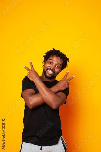 young handsome african american guy student posing cheerful and gesturing on yellow background, lifestyle people concept