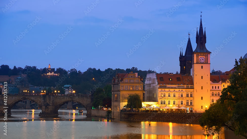 Prague, riverside in the evening. Charles Bridge and Novotnevo Lavka with a clock tower and skyline of Prague.