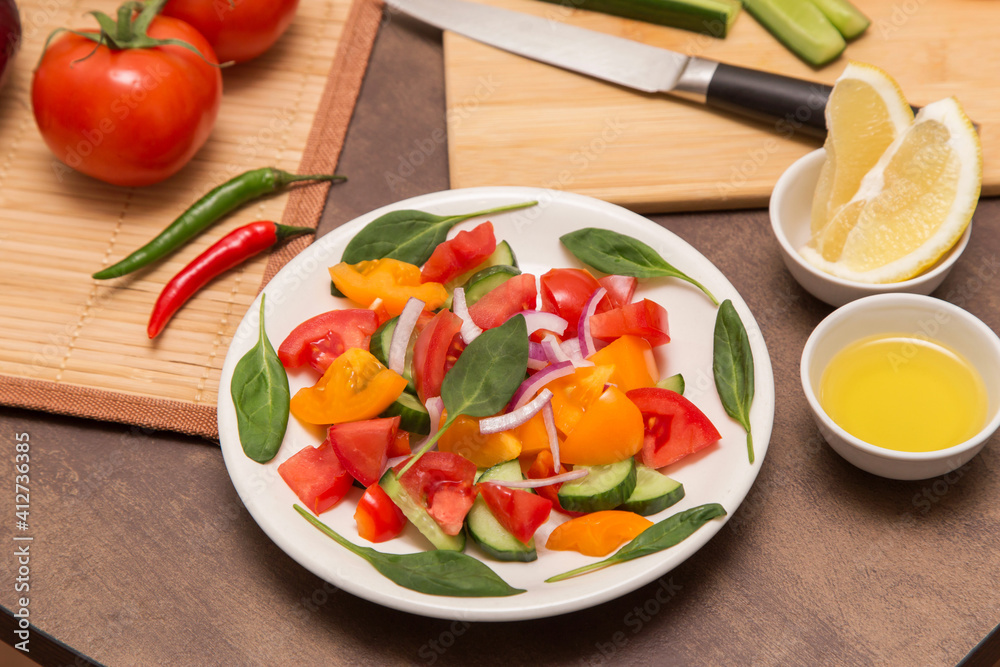 Fresh mixed vegetable salad with spinach leaves in white plate close up. Diet, vegan, vegetarian, healthy food Fresh mixed vegetable salad with spinach leaves in white plate close up. Diet, vegan, vegetarian, healthy food