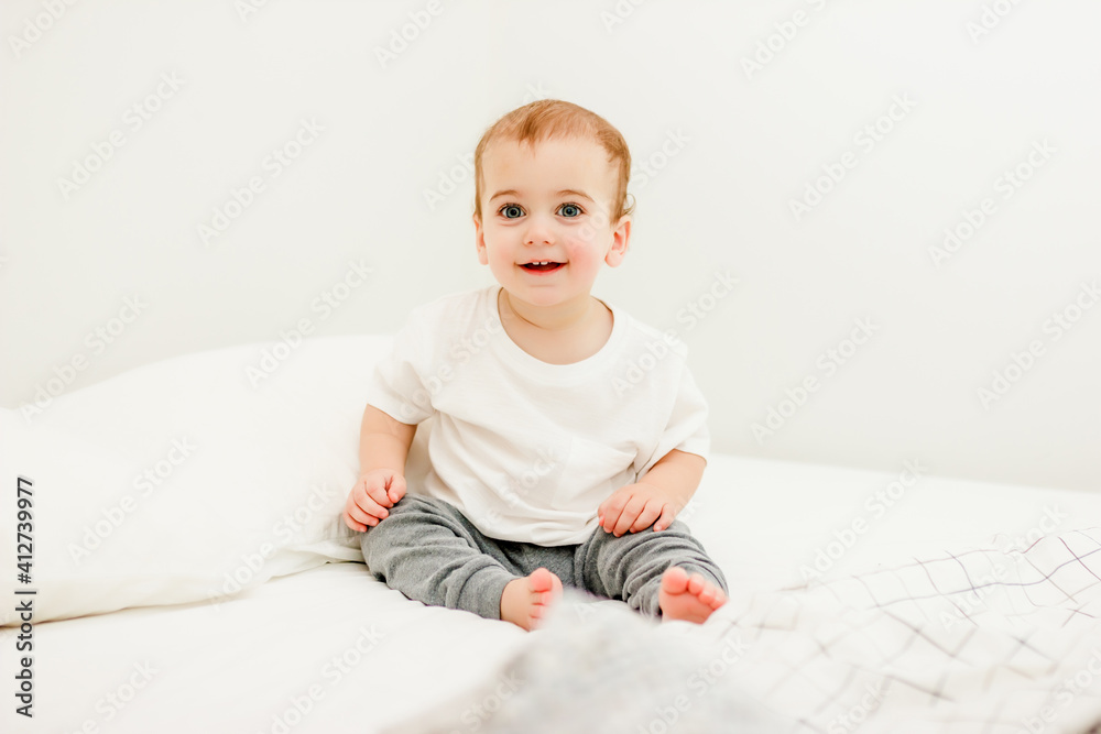 sitting baby in white tshirt on bed at home sitting baby in white tshirt on bed at home
