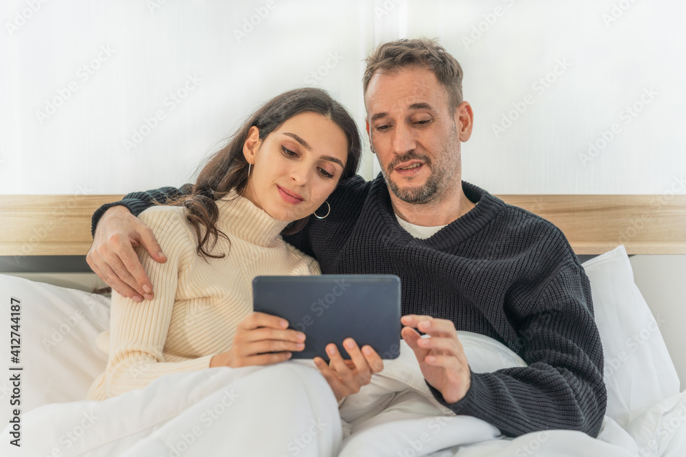 caucasian couple having good time using tablet computer together on bed in bedroom at home caucasian couple having good time using tablet computer together on bed in bedroom at home