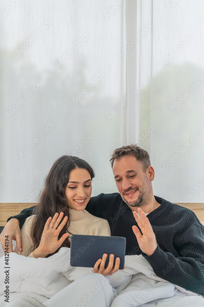 caucasian couple having good time using tablet computer making video call together on bed in bedroom at home caucasian couple having good time using tablet computer making video call together on bed in bedroom at home
