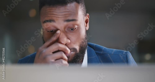 Young african businessman working overtime on laptop at office late night.