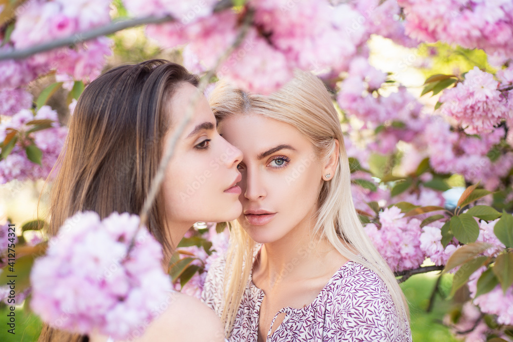 Obraz premium Spring girls fashion. Portrait of a two beautiful sensual sexy woman in cherry blossoms.