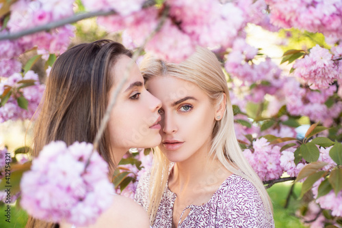 Spring girls fashion. Portrait of a two beautiful sensual sexy woman in cherry blossoms.