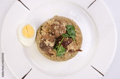 Beef Biryani Tehari cooked in mustered oil with boiled egg coriander leaf garnish on white plate over white background