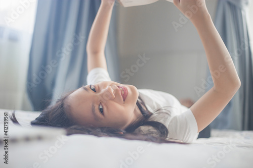 Portrait of pretty little girl reading book in bed, smiling happy and relaxed asian kid reading a book, education and school concepts