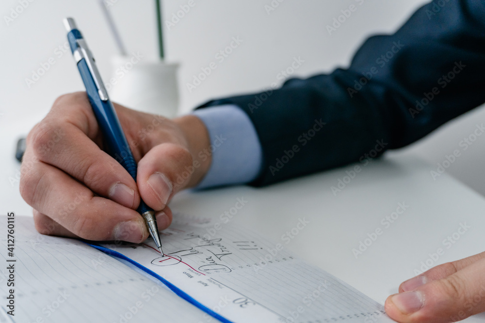 businessman writing with a mechanical pencil on his notebook businessman writing with a mechanical pencil on his notebook