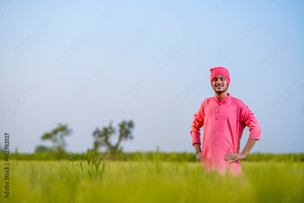 Young indian farmer standing at green wheat field Young indian farmer standing at green wheat field