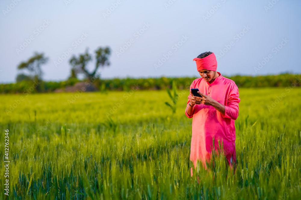 Young indian farmer using smartphone at wheat field Young indian farmer using smartphone at wheat field