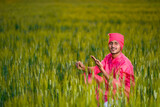 Happy young indian farmer at green wheat field