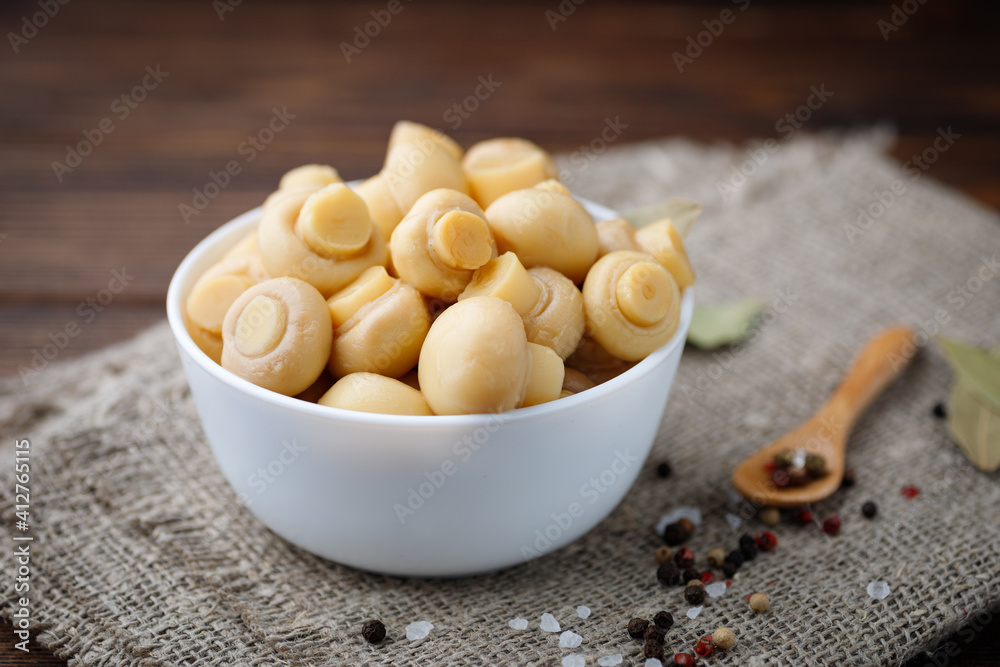 Pickled mushrooms - champignons in a bowl. Food preserving. Pickled mushrooms - champignons in a bowl. Food preserving.