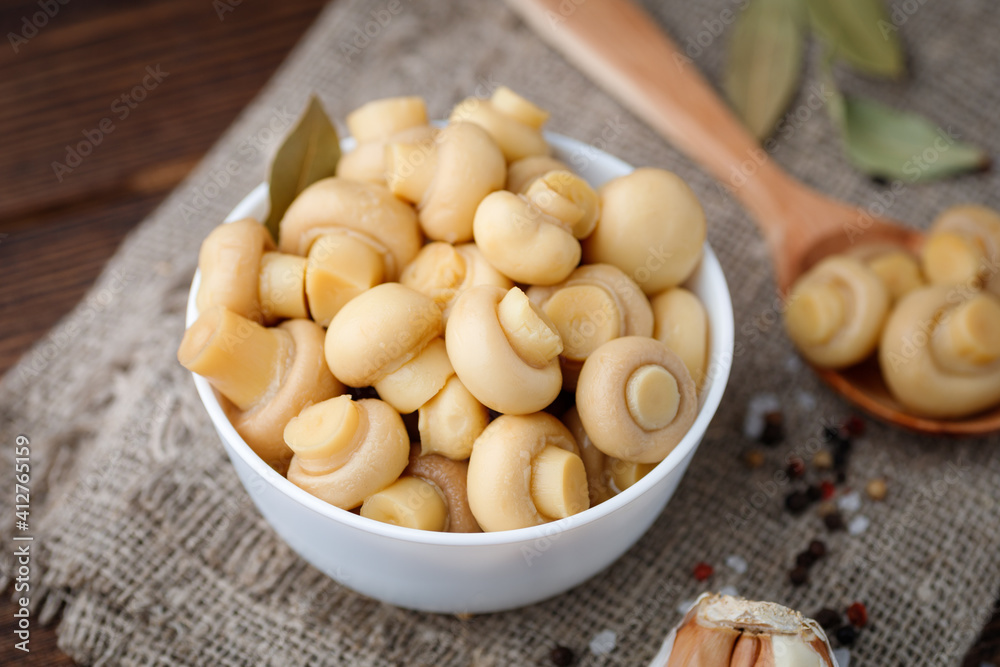 Pickled mushrooms - champignons in a bowl. Food preserving. Pickled mushrooms - champignons in a bowl. Food preserving.