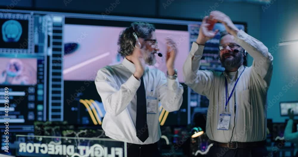 Middle aged operators watching and celebrating mission success