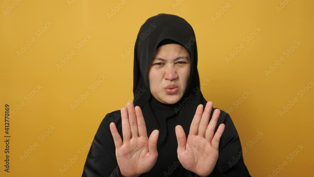 Beautiful Asian musim woman afraid expression with hands raised up, surrender gesture, over yellow background Beautiful Asian musim woman afraid expression with hands raised up, surrender gesture, over yellow background