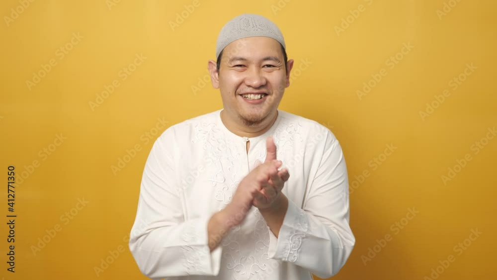 Happy proud Asian muslim man clapping gesture, half body portrait on yellow background Happy proud Asian muslim man clapping gesture, half body portrait on yellow background