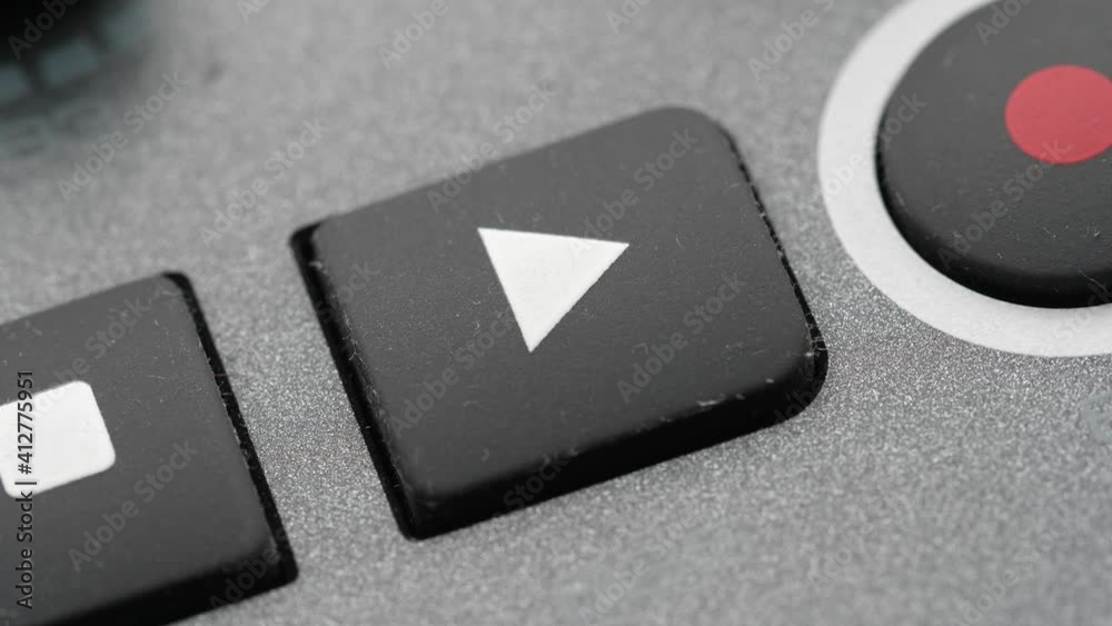 Close up of a finger pressing the play button on a device