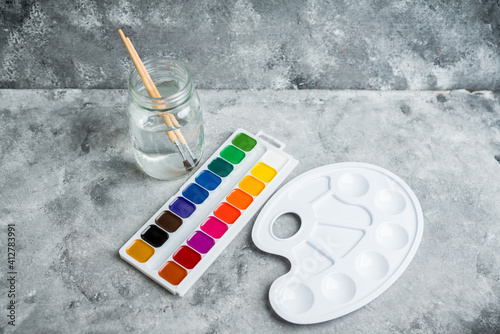 Artistic brush palette jar with water and watercolor paints