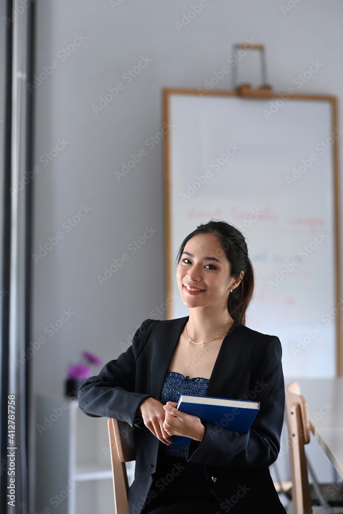 Portrait of attractive businesswoman in suit hold documents folder while sitting in modern office. Portrait of attractive businesswoman in suit hold documents folder while sitting in modern office.
