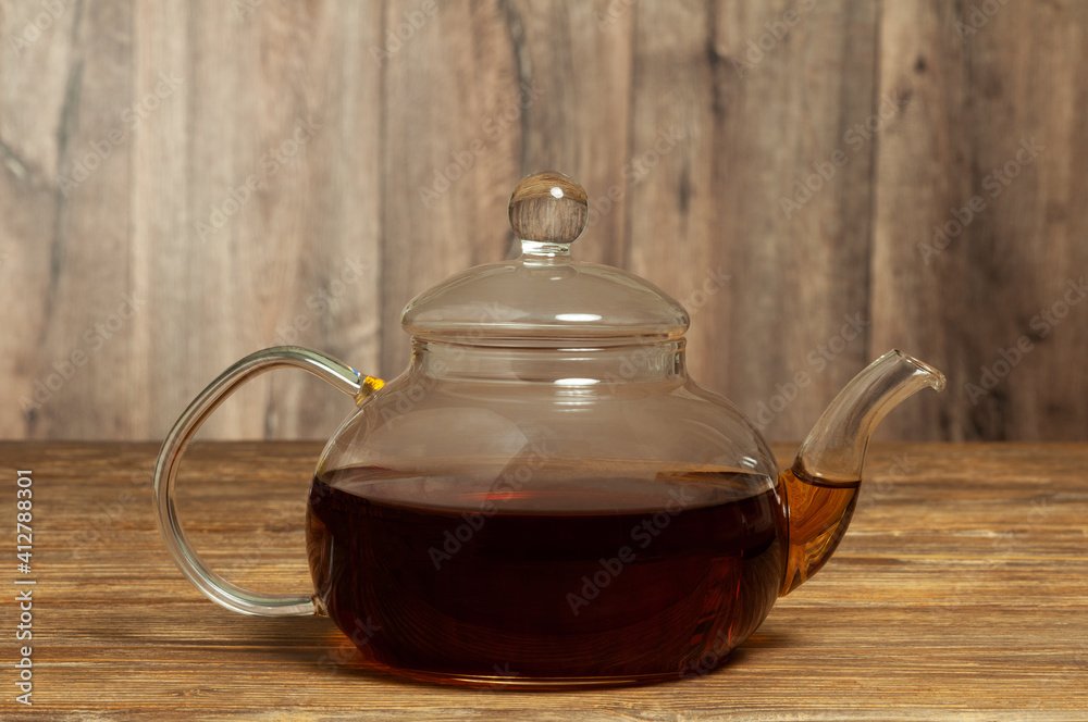 Glass teapot with tea on a wooden table. Close-up Glass teapot with tea on a wooden table. Close-up