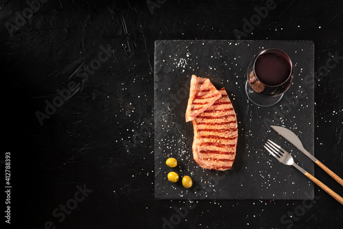 Grilled beef steak with red wine, medium, overhead shot on a dark background with copy space