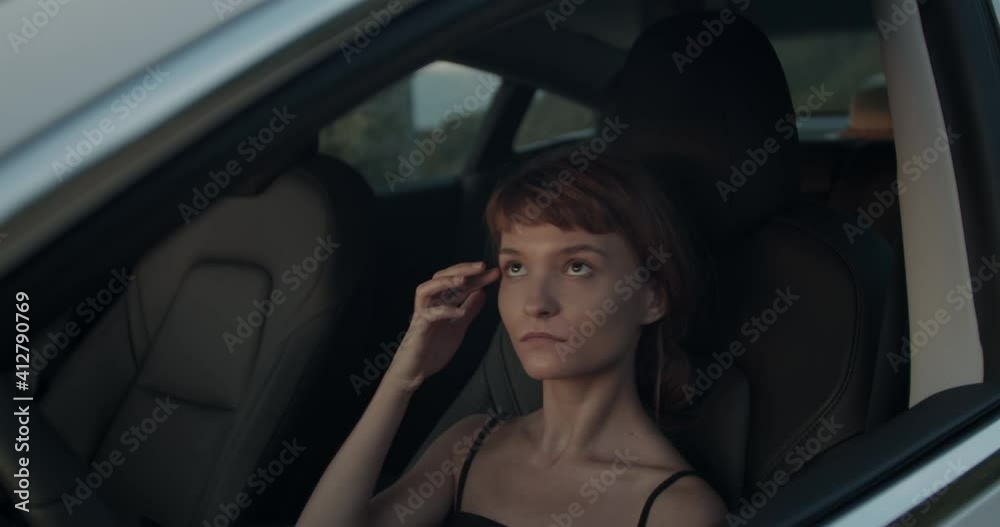 Cute girl in an electric car looking checking her hair and makeup on mirror. Handheld video Cute girl in an electric car looking checking her hair and makeup on mirror. Handheld video