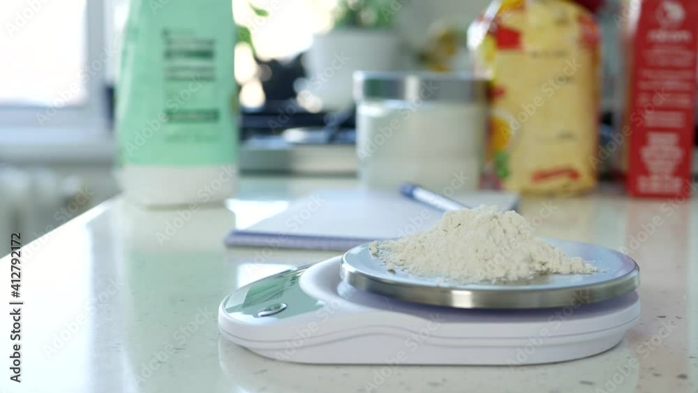 Chef in the Kitchen Weighs a Quantity of White Flour Using an Electronic Scale