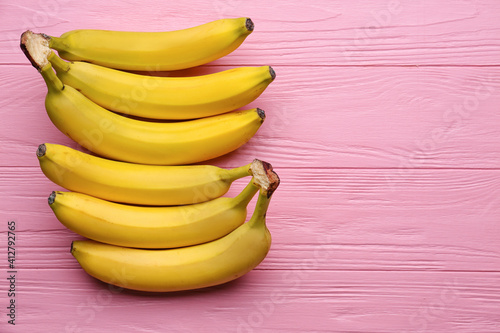 Tasty bananas on color wooden background