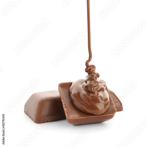 Pouring of melted chocolate on candies against white background