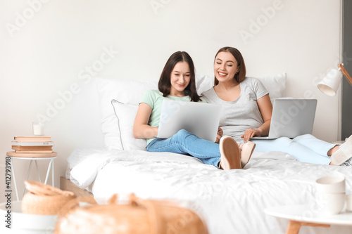 Young lesbian couple with laptops at home © Pixel-Shot