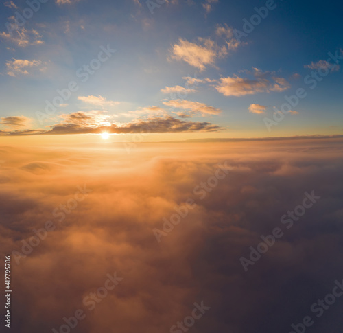 view from an airplane on a beautiful saturated sunrise above the clouds © yelantsevv