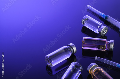 Syringes, small bottles, glass vials with vaccine, medicine on a dark blue background. Coronovirus vaccination, vaccine clinical trials,Medical Research