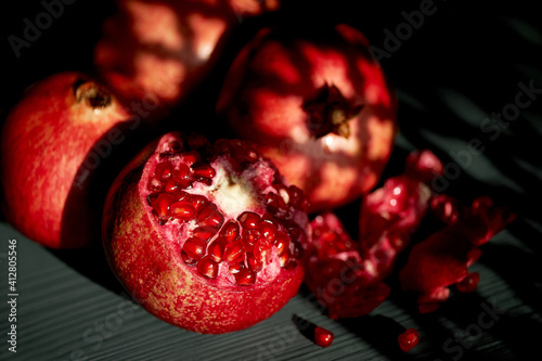 Pomegranate on a black background. Shadow from the sun's window.Whole and seeds. Vitamins in hot climates.