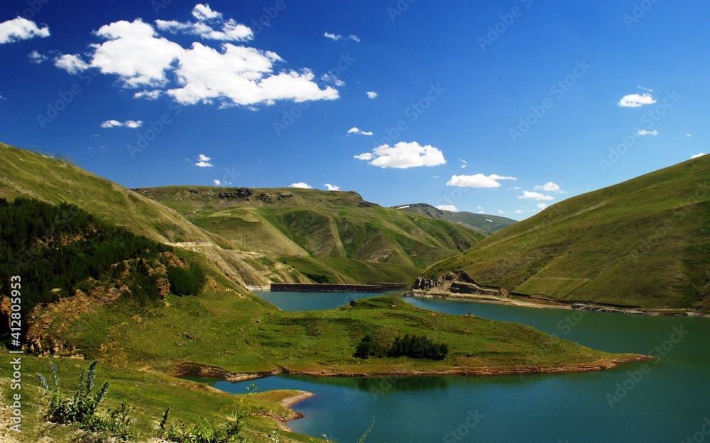 Fototapeta premium A view of a lake surrounded by mountains and rich vegetation under the cloudy sky. Natural environments like that are very common in Turkey. There are lakes more than 120 in Turkey.