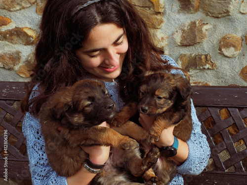 young woman with two little puppies on her hands