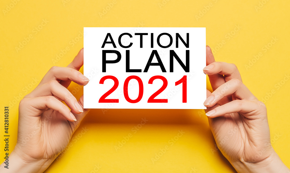 Female hands hold card paper with text ACTION PLAN 2021 on a yellow background. Business and finance concept Female hands hold card paper with text ACTION PLAN 2021 on a yellow background. Business and finance concept