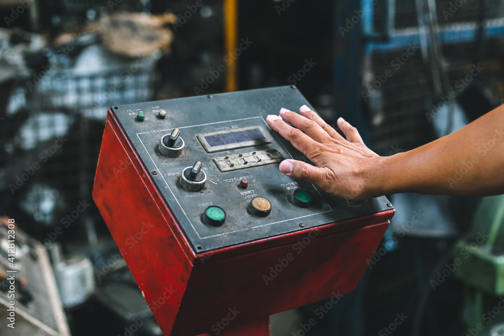 Fototapeta premium Close up hand of machine engineer are pressing button power switch to execute machine in factory.