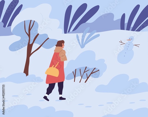 Woman walking in winter park with trees covered with snow. Side view of femal...