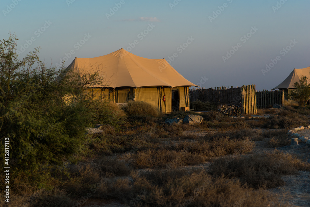 Beige tent  with beautiful sunrise and mountains on the background.  Eco retreat in the mountains. 