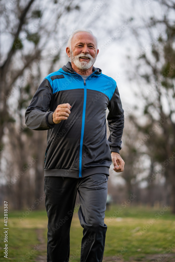 Happy senior man is jogging in park.