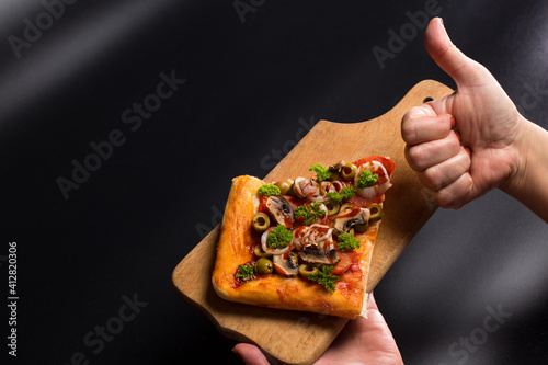 Thumb up for pizza. Piece of pizzza on wooden board. Thumb up for vegan pizza. photo