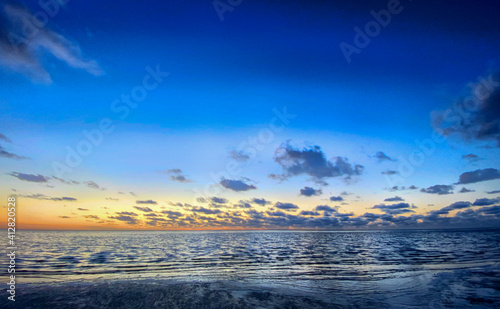 View of the setting sun shining on the Sea and reflected on the beach  clouds with sun-shining edges. Landscape. High quality photo