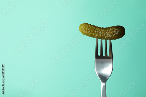 Fork with pickled cucumber on mint background photo